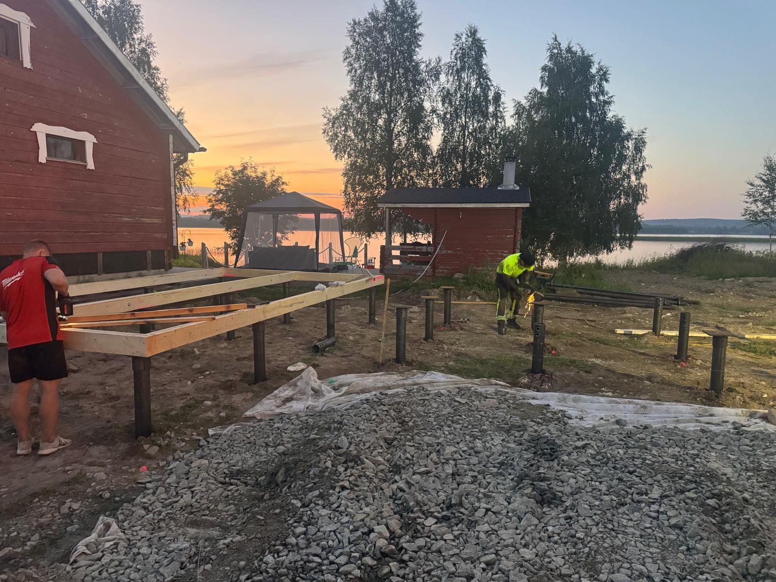 Operarios montando estructura de madera sobre cimentaciones con pilotes helicoidales junto al lago