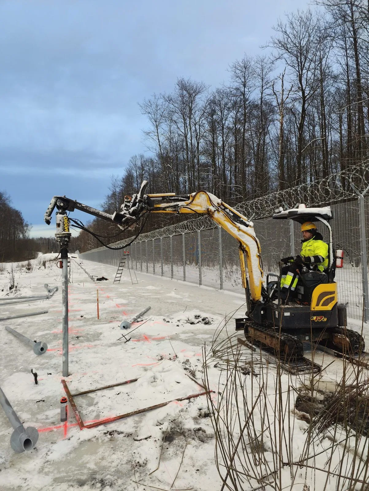 Miniexcavadora instal·lant un pilot helicoïdal en terreny gelat